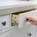 Male hand pulling and opening drawer on white wooden cabinet. Home furniture and decoration shopping concept